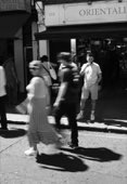 Black and white street scene, people crossing in bright sun