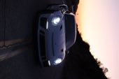 A Porsche with its headlights on at dusk