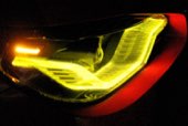 A car headlight burning yellow against the dark