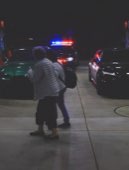 Two figures on a street at night, lit by police lights